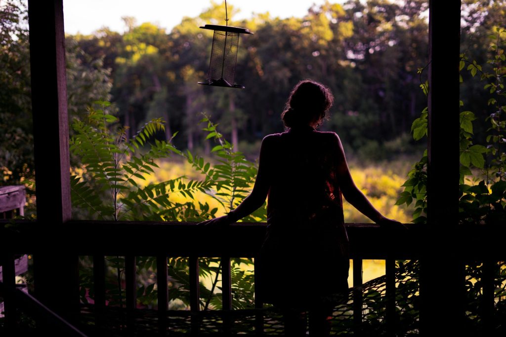 woman in black dress standing on brown wooden bridge during daytime